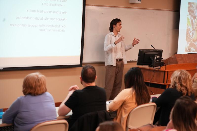 LMU under研究生 student presenting his 研究 to a crowd.