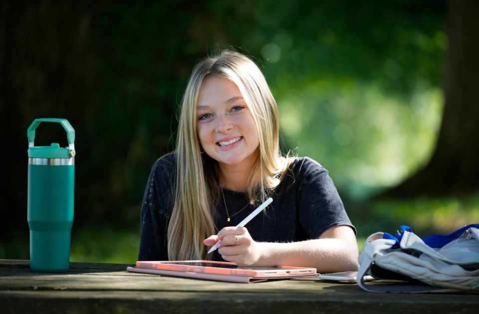 A picture of a student studying at a picnic table. 