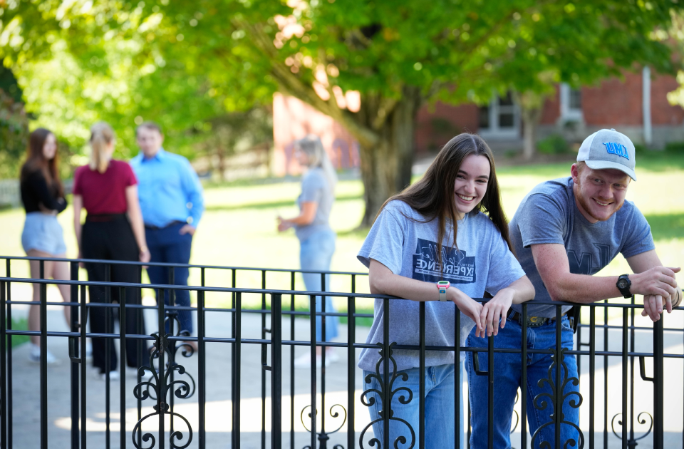 A picture of two students leaning against a rail. 